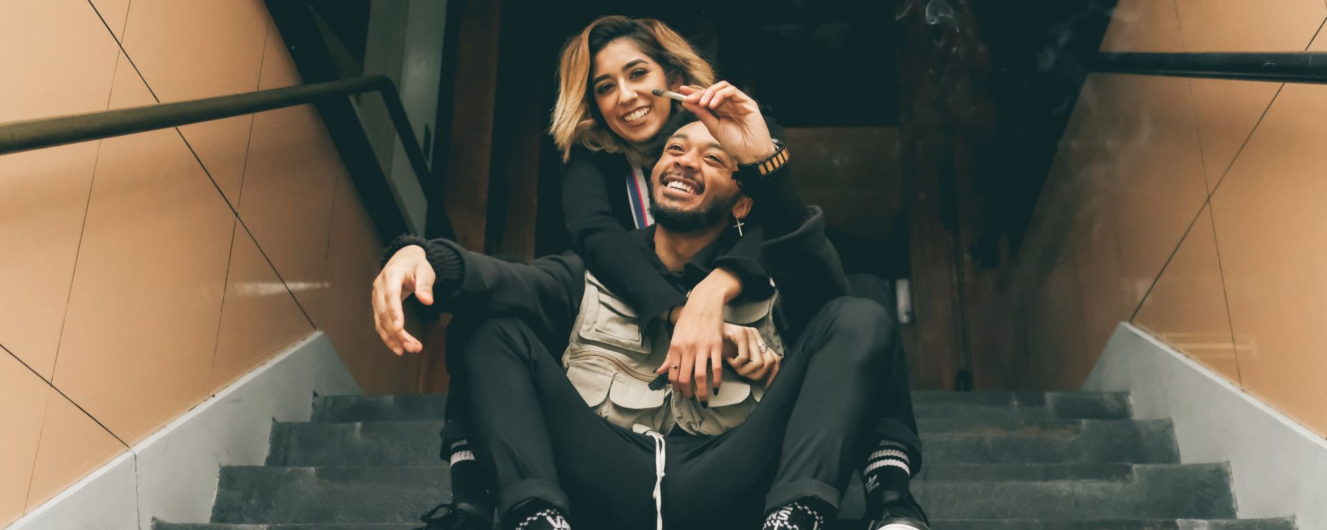Man and woman sitting on steps using cannabis