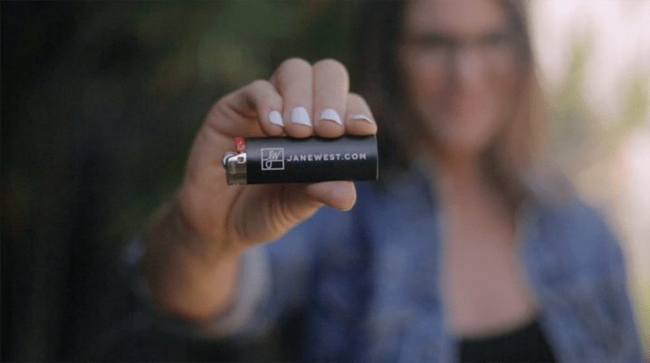 Cannabis entrepreneur Jane West holding a lighter with her company name
